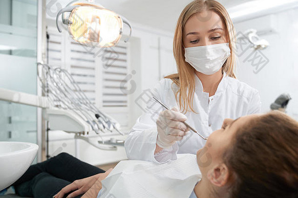 专业牙医穿医疗面具手套白色统一的医生治疗牙齿病人防止龋齿女人说谎牙医椅子口腔学概念