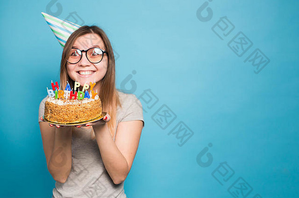 关闭有趣的积极的女孩眼镜问候纸他持有快乐生日蛋糕手站蓝色的背景复制