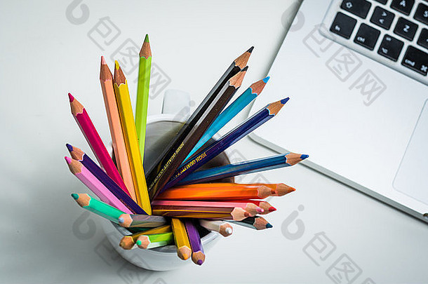 <strong>创意</strong>工作区内的一组彩色铅笔和一台笔记本电脑