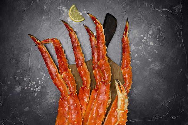 新鲜的王堪察加半岛螃蟹的爪柠檬片木董事会黑色的背景