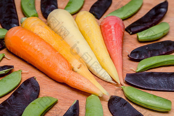 五种不同颜色的胡萝卜，周围有紫色的芒果和糖豌豆