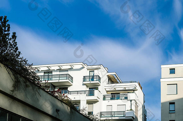 在晴朗的天气里，美丽的蓝天和散落的云朵点缀着现代化的公寓楼，有窗户和阳台
