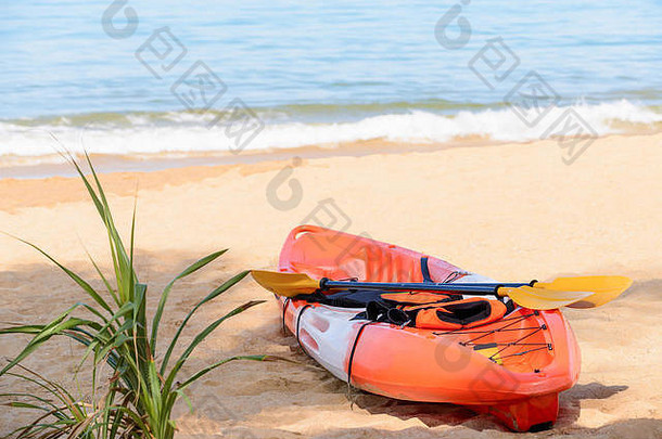 阳光明媚的日子里，沙滩上的独木舟，带着桨和救生衣。