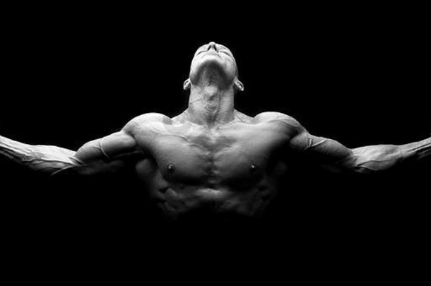 张开双臂的强壮运动员。强壮的健美运动员，有六块腹肌，完美的腹肌、肩部、二头肌、三头肌和胸部，黑色背景