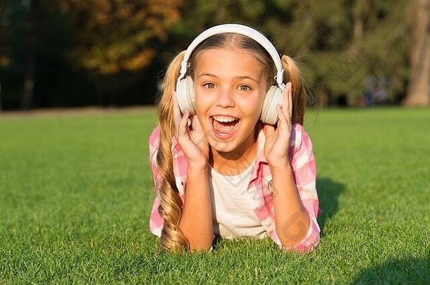 小女孩听音频书技术孩子们快乐童年记忆听音乐回来学校孩子研究公园放松绿色草耳机钩状的学习
