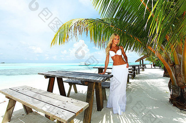 女人坐着热带咖啡馆背景棕榈树天空海