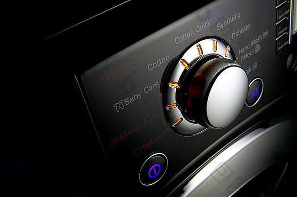 现代洗衣机控制面板的特写镜头，在黑色背景下带有定时器和选项键