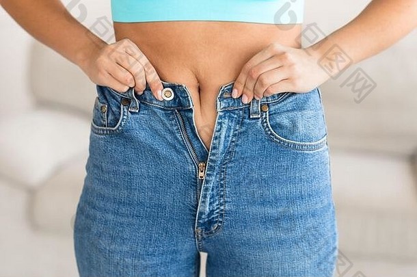 一名妇女在体重增加后试图拉上牛仔裤拉链，结果被剪短
