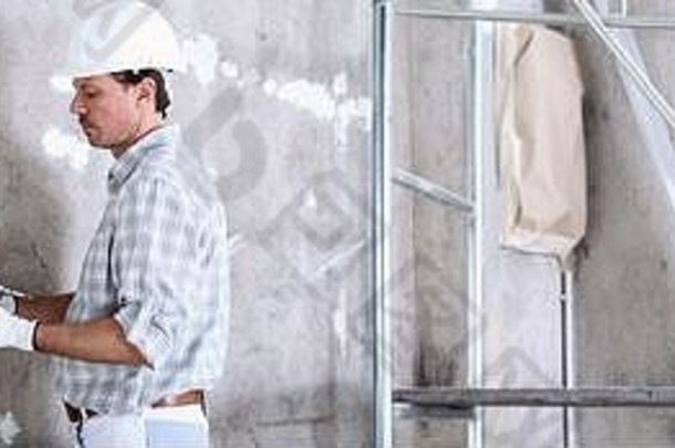 粉刷工男人。工作泥刀抹墙室内建设网站穿头盔保护手套白色墙复制空间