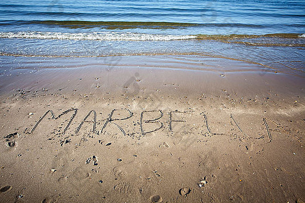 Marbella这个词写在海滩的湿沙上