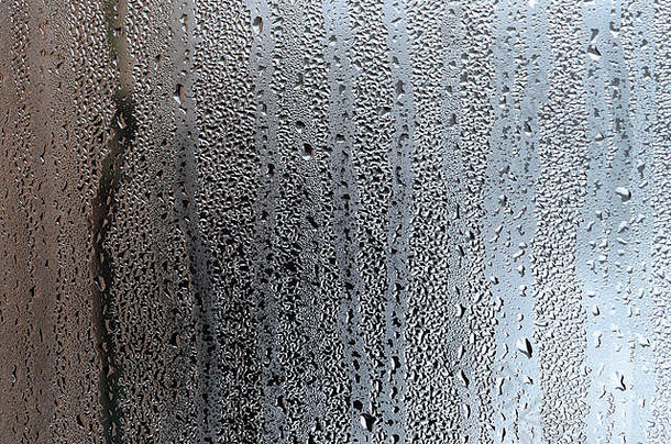 雨滴在玻璃湿透明背景上的纹理。灰色调的。