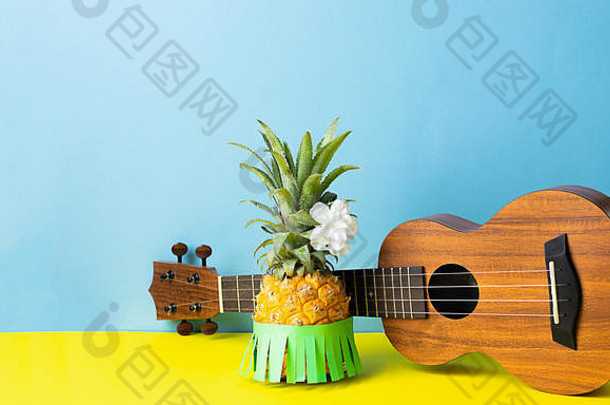 穿着绿色夏威夷裙的成熟<strong>菠萝</strong>。小吉他蓝黄色背景。夏威夷夏季派对嘉年华的概念。