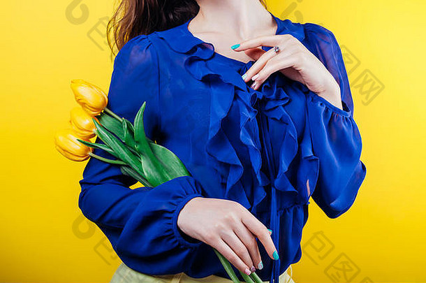 摄影棚拍摄了一位身穿春装、手持黄色郁金香、背景为黄色的女士