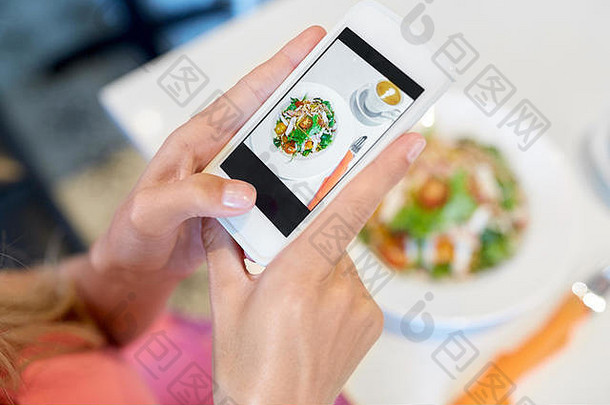 在咖啡馆用智能手机拍摄食物的女人