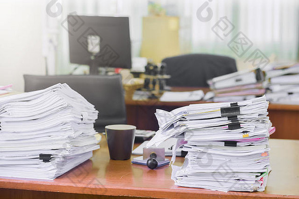 办公桌上堆积如山的文件、业务文件、账单和检查报告汇总结果、年度报告