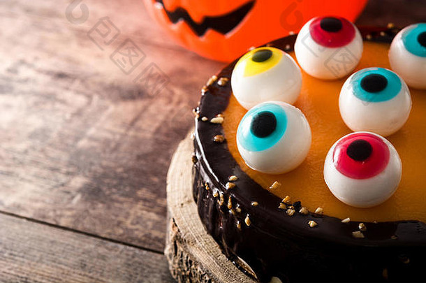 木制桌子上有糖果眼装饰的万圣节蛋糕。版面