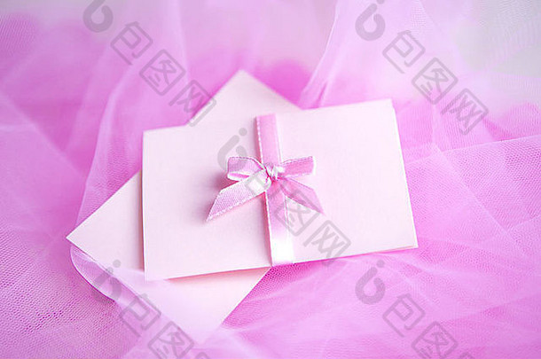 织物背景上有缎面蝴蝶结的粉色硬纸板