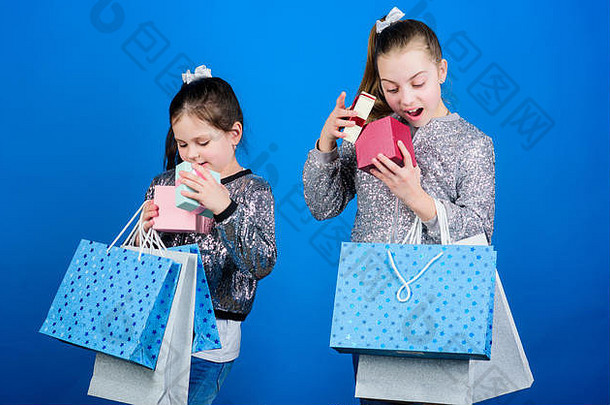 购物日。儿童时尚。带蓝色背景购物袋的女孩姐妹朋友。交付给您的所有产品。购物和购买。黑色星期五。销售和折扣。孩子们把包裹捆起来。