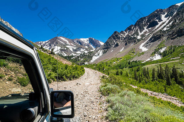 吉普车在锡耶拉的土路上行驶，有山峰和绿色山谷