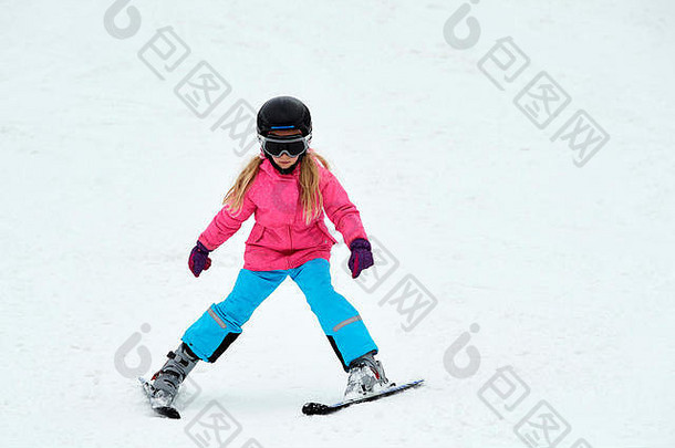 孩子们在山上滑雪。穿着五颜六色西服和安全帽的女孩正在学习滑雪。有小孩的家庭冬季运动。儿童滑雪第一课