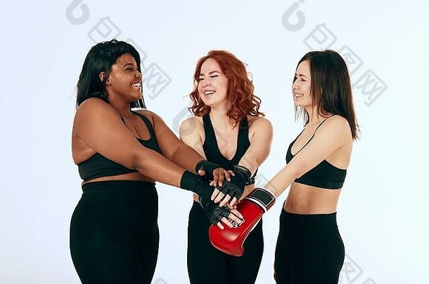 三位不同<strong>文化背景</strong>的女朋友戴着<strong>红色</strong>拳击手套和黑色手套在白色<strong>背景</strong>下击掌