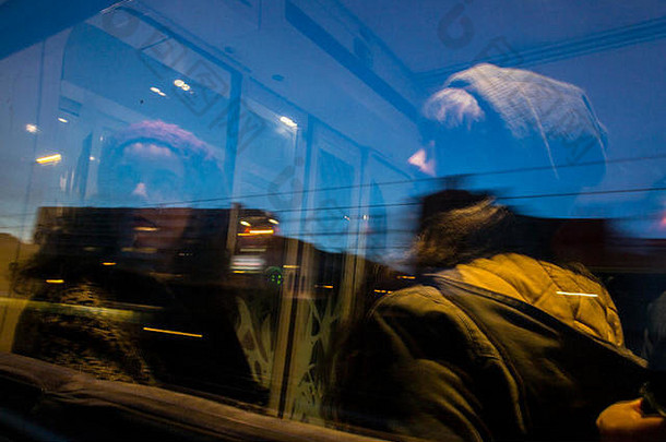两个女孩在火车上看着窗外。“蓝色小时”期间的城市景观。