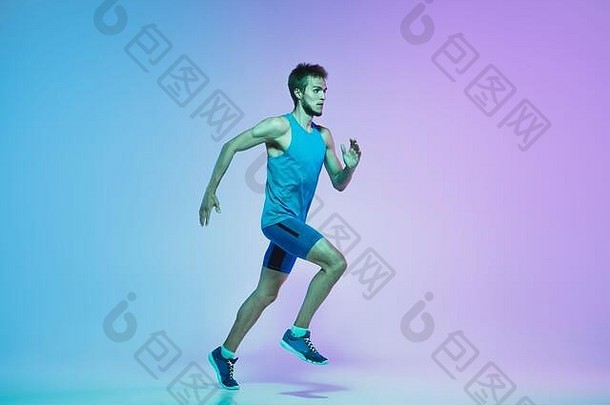 活跃的白人年轻男子在霓虹灯下在渐变工作室背景上跑步的肖像。专业运动员的动作训练。运动、健康、活动、活力概念。