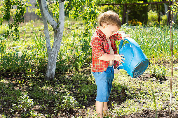 一个可爱的小男孩用蓝色的水罐往脚上浇水。