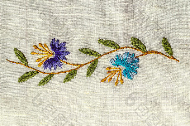 亚美尼亚埃里温，2018年6月4日：粗棉布上绣有叶子的紫色和蓝色矢车菊的刺绣缎纹波浪小枝