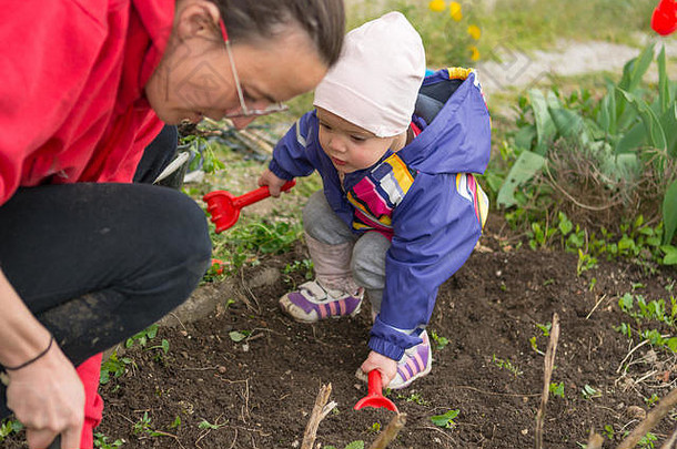 小女孩探索花园，帮助进行春季大扫除。