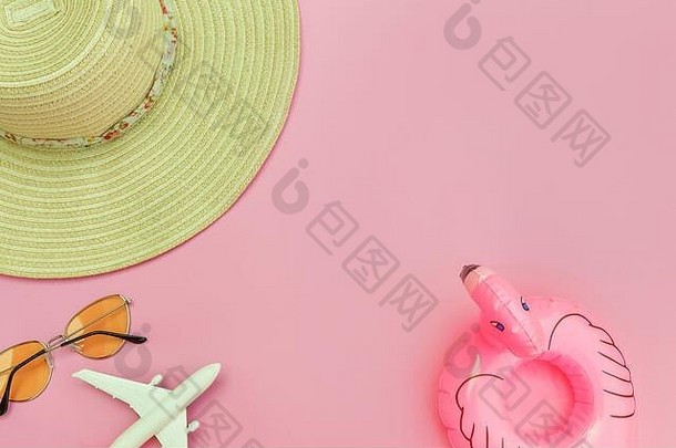 夏季海滩组成。简约的平铺，带有平面太阳镜、帽子和可充气的火烈鸟，在柔和的粉色背景上进行隔离。度假旅游探险旅游概念。俯视空间