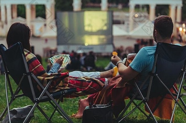 夫妇坐着camp-chairs城市公园电影在户外开放空气电影