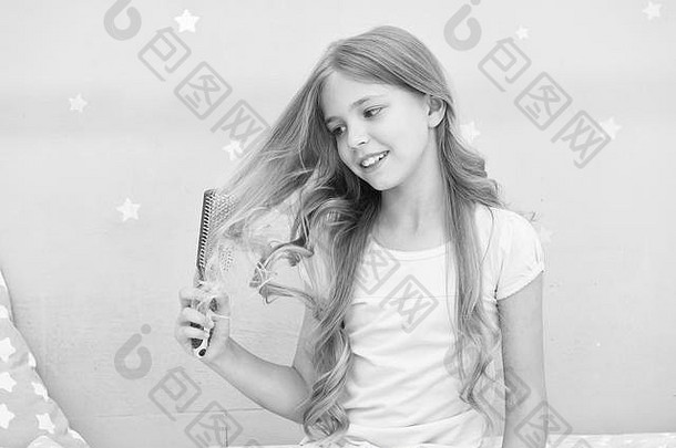 孩子卷曲的发型持有毛刷梳子应用石油梳理头发健康的头发护发<strong>素面</strong>具有机石油梳子头发美沙龙提示女孩长卷曲的头发灰色室内背景