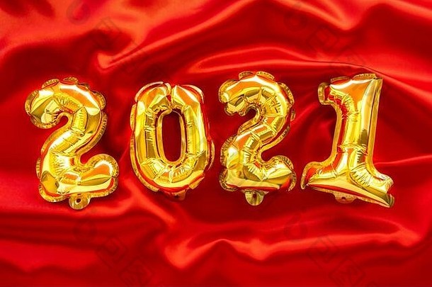 以2021号为形式的金属箔气球。新年庆典。红色节日背景上的金色气球。节日派对装饰。顶视图。