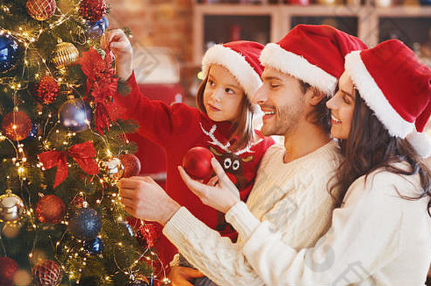 可爱的女孩帮助<strong>父母</strong>装饰圣诞树