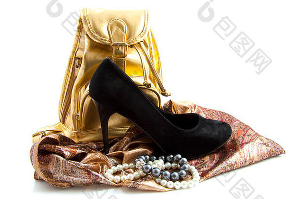 金色包，前面有黑色高跟鞋和装饰布上的珠宝