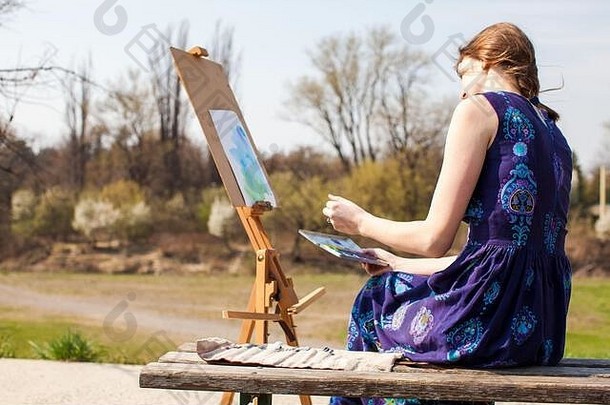 这位年轻的女创意画家在户外的画布上画毛笔水彩画。春天的灵感。