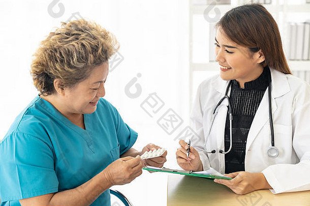在诊所的检查室里，一位亚洲女医生正在给老年病人开药方。