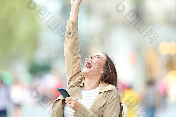 兴奋女人持有聪明的电话尖叫提高手臂庆祝好新闻在户外街