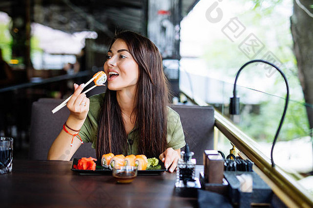 美丽的女孩享受寿司咖啡馆阳光明媚的一天