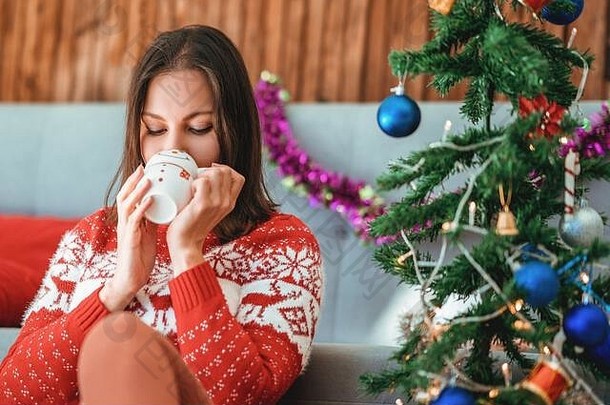 年轻女子坐在<strong>咖啡</strong>馆里，拿着雪人杯喝酒。圣诞节的概念。