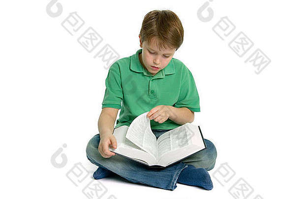 年轻的男孩坐交叉腿把页面参考书阅读拍摄白色背景