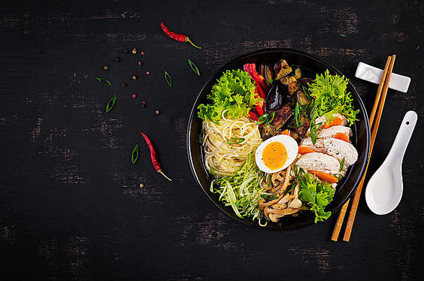 日本拉面汤，黑色木质背景，配鸡肉、鸡蛋、石磨蘑菇和茄子。相扑汤。俯视图