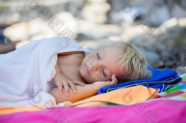 蹒跚学步的孩子睡在沙滩上，夏日为孩子们放松