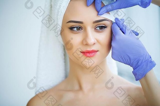 美容师打蜡年轻的女人的眉毛水疗中心中心