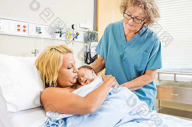 护士帮助年轻的女人新生儿婴儿