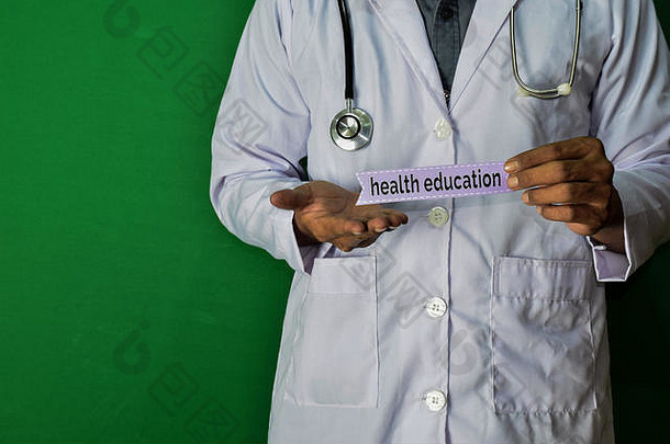 一位医生站着，手持绿色背景上的<strong>健康教育</strong>纸文本。医疗保健概念。