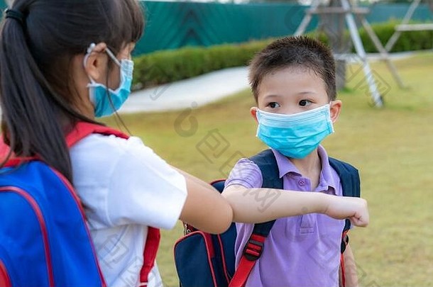 肘撞是一种新的避免冠状病毒传播的问候语。两位亚洲儿童学前班的朋友赤手空拳在学校公园相遇。因斯蒂亚