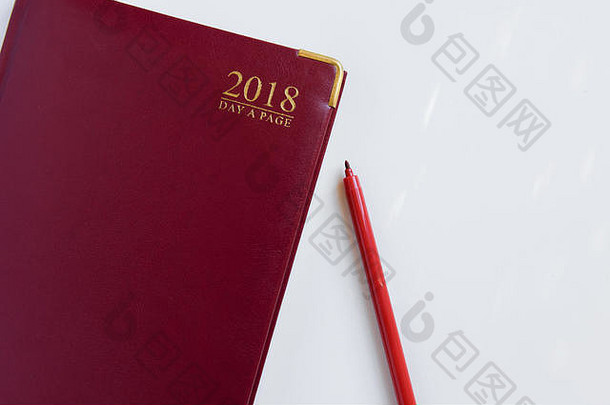2018年红色日记的俯视图，白色背景上的笔和文本空间