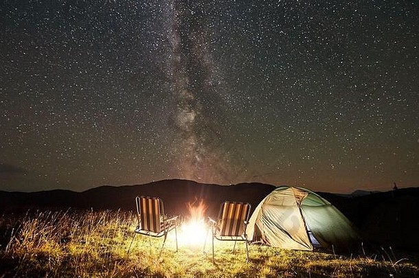 旅游野营晚上山发光的帐篷椅子篝火令人难以置信的美丽的晚上天空完整的星星乳白色的旅游冒险生活方式天体摄影术概念